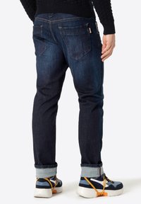 Donkerblauwe denim jeans met een slim fit, met achterzakken en een omgeslagen zoom, gecombineerd met kleurrijke sneakers met een dikke zool.