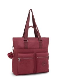 Bordowa torba na ramię z dwiema przednimi kieszeniami na zamek, długimi i krótkimi uchwytami oraz małym pluszowym breloczkiem w kształcie małpki.