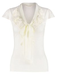 Bílý top s krátkým rukávem, zdobený volánkovým výstřihem a zavázanou saténovou mašlí. Vyrobeno z měkké látky, s přiléhavým střihem a hladkou texturou.