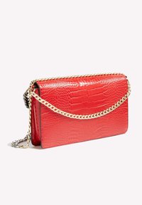 Bolso crossbody de cuero rojo con relieve de cocodrilo, con una cadena dorada y cierre de solapa, que muestra una textura suave y una forma estructurada.