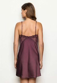 Donna vista di spalle che indossa un abito in satin bordeaux senza maniche, con dettagli in pizzo sulla parte superiore della schiena e spalline sottili e regolabili.