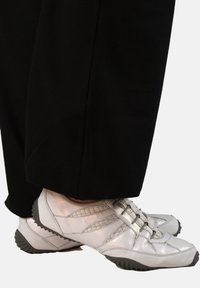 Silver leather shoes with a textured finish, featuring a streamlined design and a rubber sole, paired with black pants.
