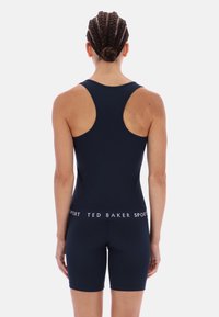 Tengerészkék sportos egyberuha versenyháti kialakítással, testhezálló szabással és fehér "TED BAKER SPORT" derékpánttal. Simított textúra.