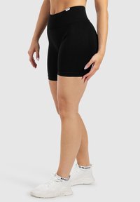 Zwarte high-waisted fietsshorts van rekbaar materiaal, met een subtiele glans, een zachte textuur en een aansluitend ontwerp.
