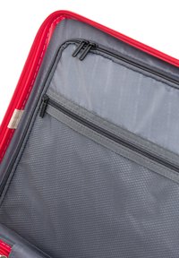 Interno di una borsa da viaggio rossa caratterizzato da una fodera grigia liscia, tasca in rete con zipper e un motivo stampato con il nome del marchio. Zipper di colore nero.