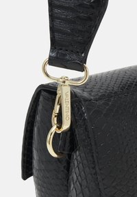 Svart texturerad läderhandväska med ett lås i guld och remfäste, med ett reptilmönster och en elegant, strukturerad design.