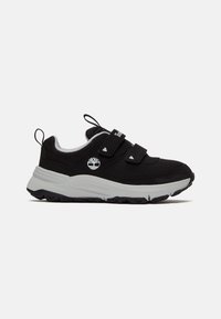 Chaussures de sport en mesh noir avec des accents gris, dotées de deux sangles Velcro, d'une semelle épaisse noire et blanche, et d'un logo sur le côté.