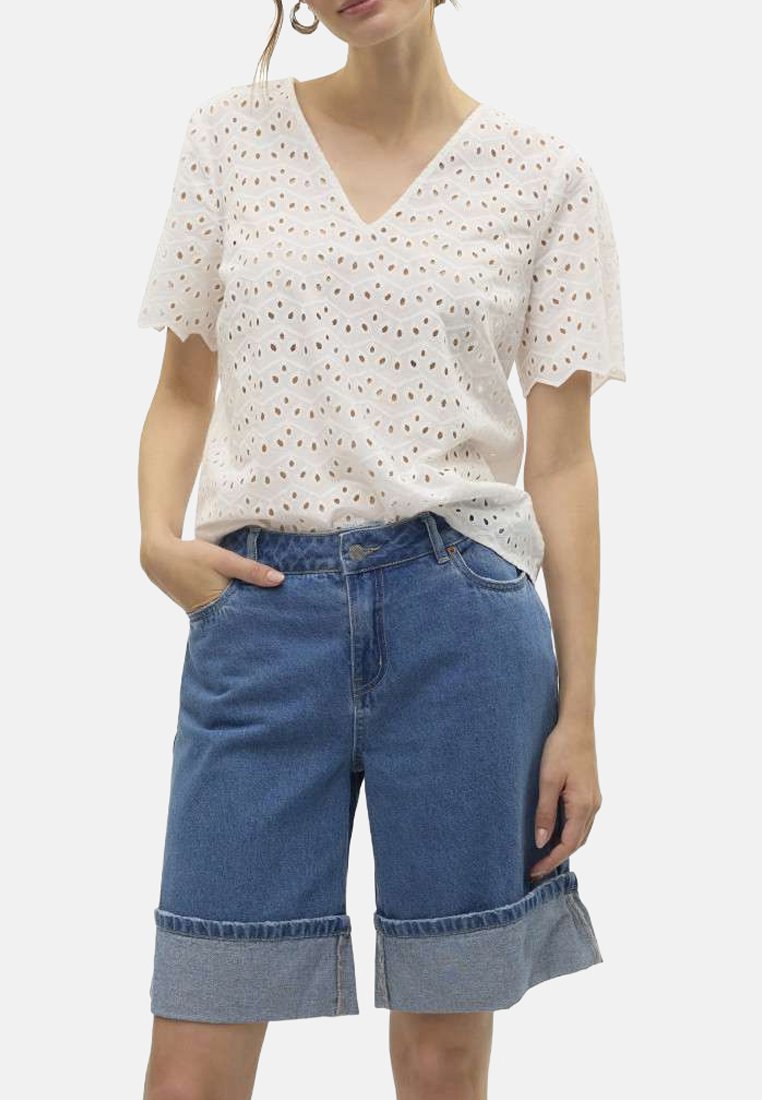 Haut en eyelet blanc avec un col en V, associé à un short en jean bleu avec un ourlet replié, affichant une texture lisse et une coupe décontractée.