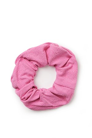 Goma para el pelo scrunchie de tela suave rosa con superficie texturizada sobre fondo blanco.