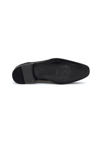 Semelle de chaussure en cuir noir avec une surface texturée, bout rond et design en relief. Détails de couture sur le bord et motif de crampons en caoutchouc.