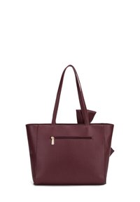 Bordeaux faux leren tote bag met twee handvatten, decoratieve strikdetails en een ritsvak aan de buitenkant voor extra functionaliteit.