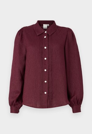 Burgundy long-sleeve button-up shirt with a collar, featuring pleats and decorative buttons. Made from textured fabric, with gathered sleeves.
