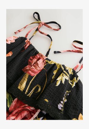 Čierne šaty s kvetinovým vzorom, na ktorých sú ružové a žlté kvety, nastaviteľné ramienka, smockovaný korzet a čipkový lem na spodnej strane.