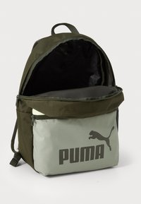 Rugzak met een donkergroene stof buitenkant, grijs onderste compartiment met groot zwart "PUMA" logo, ritsluiting en dubbele schouderbanden.