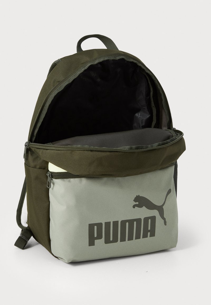 Sac à dos avec un extérieur en tissu vert foncé, un compartiment inférieur gris avec un grand logo noir "PUMA", fermeture éclair et bretelles doubles.