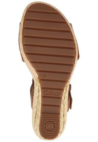 Semelle en caoutchouc marron d'une sandale avec des rainures horizontales et des côtés en jute tissée, marquée du mot Gabor et d'un logo circulaire G près du talon.