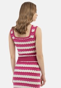 Top lavorato a maglia con motivo zigzag magenta e crema, dotato di scollatura quadrata e vita aderente. Presenta una banda a coste nella parte inferiore.