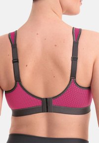 Biustonosz z różową siateczką o fakturze z tyłu, szarymi ramiączkami i pasem dolnym, z regulowanymi ramiączkami oraz zapięciem na haftkę.