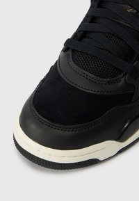 Μαύρα αθλητικά παπούτσια με συνδυασμό λείων και σουέντ υφών, στρογγυλή μύτη, επενδεδυμένο κολάρο και υφασμάτινη σόλα από καουτσούκ με αντίθετη ρίγα.