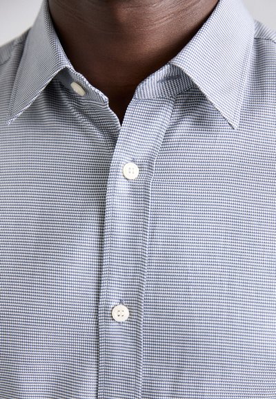 Button-down shirt in a blue and white gingham pattern, featuring a structured collar and white buttons on the front. Textured fabric visible.