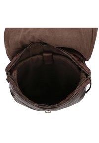 Bruine leren rugzak met een ruime binnenkant, voorzien van een ritssluiting en zachte stoffen voering. De bovenflap is gemaakt van bruin canvas.