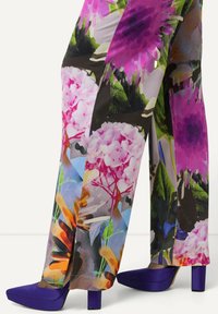 Bloemendruk brede broek met levendige roze, paarse en groene tinten. Gecombineerd met paarse blok hak schoenen voor contrast.