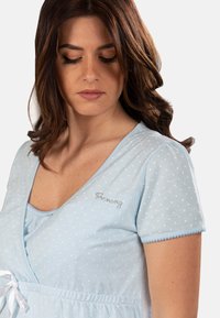 Camicia da notte azzurro chiaro a pois, con scollo a V, maniche corte e vita regolabile con coulisse. Presenta ricami con accenti di cristallo sul petto.