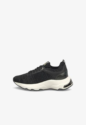 Zwarte sneaker van gebreide stof met zwarte veters, een witte dikke zool en een metalen hieldetail, afgebeeld vanaf de buitenkant op een witte achtergrond.