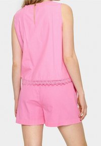 Haut en coton rose avec un ourlet en dentelle et une ouverture en forme de clé au dos. Associé à un short rose assorti. Design simple et décontracté.