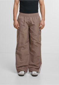 Bruna cargobyxor med elastisk midja, vida ben och sidofickor. Tyget verkar slätt och har subtila sidostrikar vid fållen.