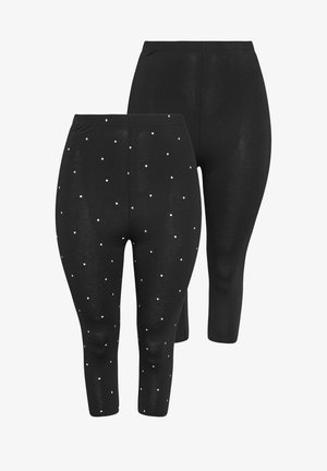 Zwei Paar schwarze, gekürzte Leggings, eins einfarbig und eins mit kleinen weißen Punkten, Vorderansicht auf weißem Hintergrund gezeigt.