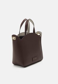 Borsa in pelle marrone con parte superiore arrotondata, doppi manici, fodera beige, dettagli in metallo dorato e un piccolo tag con logo alla base.