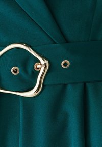 Teal fabric with a smooth texture features a wide belt with an irregular gold buckle and two gold grommets for fastening at the waist.