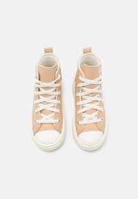 Zapatillas altas beige hechas de cuero suave, con cordones blancos, puntera de goma y cuello acolchado para mayor comodidad.