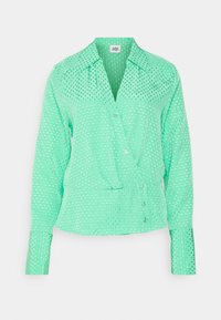Blusa verde menta com colarinho clássico, mangas longas, fecho frontal por botões e um padrão de bolinhas texturizado por todo o tecido.