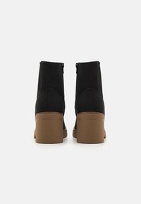 Bottines noires avec une texture lisse, un talon bloc de hauteur moyenne, des zips sur les côtés et des surpiqûres contrastantes le long du bord supérieur.