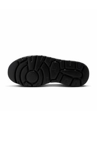 Suela de zapatilla negra con un diseño de goma texturizada, que presenta patrones circulares y lineales para mayor tracción. Confección plana con líneas definidas.