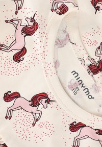 Ropa infantil con unicornios rosas y crines rojas impresas sobre tela color crema, con un escote redondeado y etiqueta de talla "5Y 110".