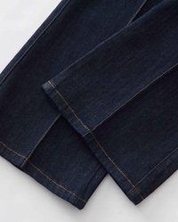 Tissu en denim bleu foncé avec une texture lisse, présentant des coutures orange contrastantes le long des coutures et de l'ourlet, replié sur les bords.