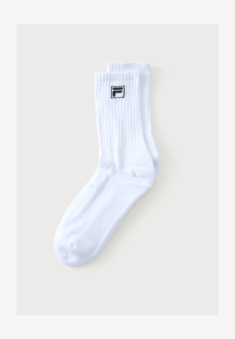 Paire de chaussettes blanches montantes avec des bords côtelés et un petit logo noir et blanc près du haut sur un fond neutre.