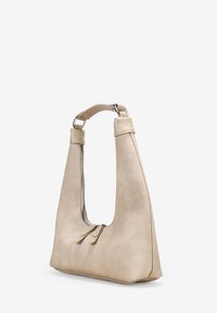 Bolso de mano de cuero beige con un diseño de corte único, textura suave, correa delgada y dos tiradores de cremallera en la parte frontal para un cierre seguro.