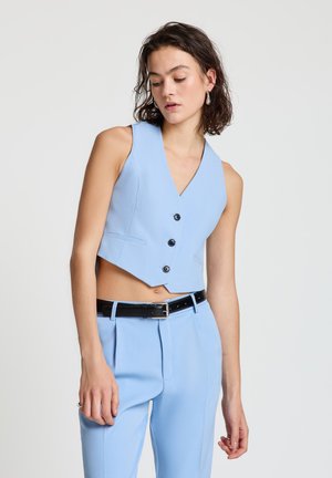 Hellblaues, kurzes Weste aus glattem Stoff mit V-Ausschnitt, drei schwarzen Knöpfen und Seitentaschen, kombiniert mit passenden Hosen.