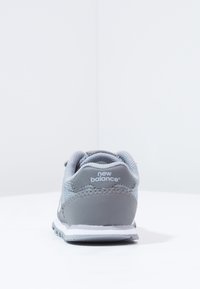 Szare sneakersy z siatkowym wierzchem i wyściełanym kołnierzem. Posiadają gumową podeszwę, logo na pięcie oraz gładkie akcenty po bokach.