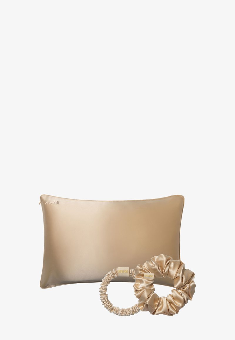 Seidene Kissenbezug in beige mit satinierter Oberfläche und glatter Textur, begleitet von einem passenden satinieren Haargummi mit elastischem Band.
