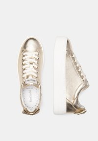 Goldfarbene, metallische Sneakers mit weißen Schnürsenkeln, kontrastierender weißer Sohle und Schleifenakzent an der Ferse. Runde Zehenpartie und glatte, glänzende Textur.