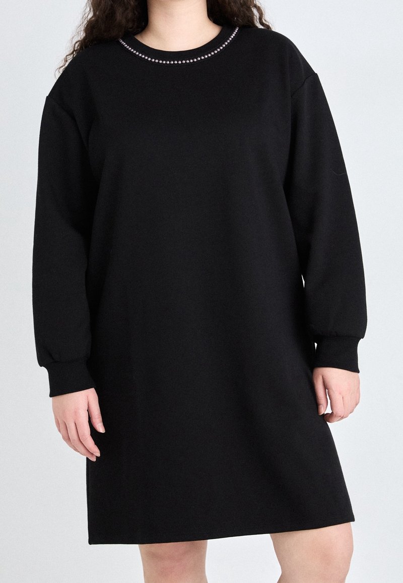 Robe sweat noire en tissu doux, avec des manches longues, une coupe décontractée et un col rond agrémenté d'un accent décoratif.