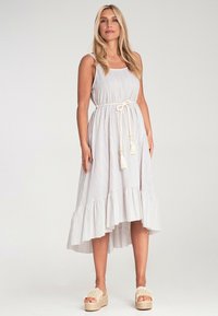 Leichtes gestreiftes Kleid in Weiß und Hellblau, mit einem Rüschensaum und einem gebundenen Gürtel mit Quasten. Getragen mit beigen Keilsandaletten.