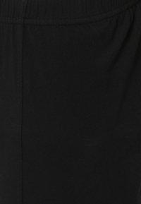 Zwarte katoenen kleding met een gladde textuur, elastische tailleband en een eenvoudig ontwerp. Close-up benadrukt de lichte kwaliteit van de stof.