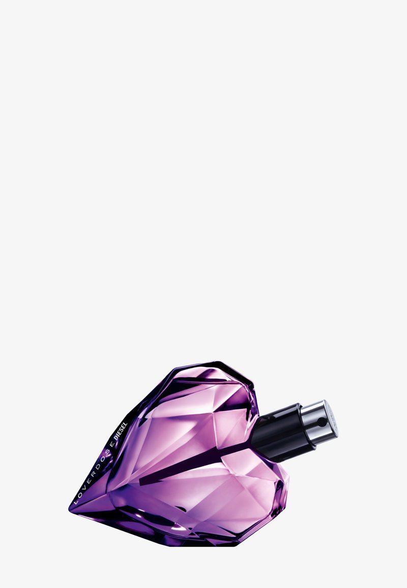 Botella de perfume de vidrio morado con forma de corazón, que presenta un diseño facetado y un pulverizador plateado. Detalles elegantes y geométricos.