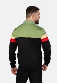 Kraagloze pullover met kleurblokontwerp: groen, geel, rood en zwart. Beschikt over lange mouwen en een geribbelde zoom. Zachte stoftextuur.